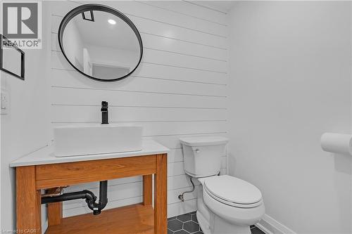 Hexagonal floor tiling, white shiplap wall, rectangular vessel sink, matte black faucet, and wood-finish vanity - 4236 Longmoor Drive, Burlington, ON 