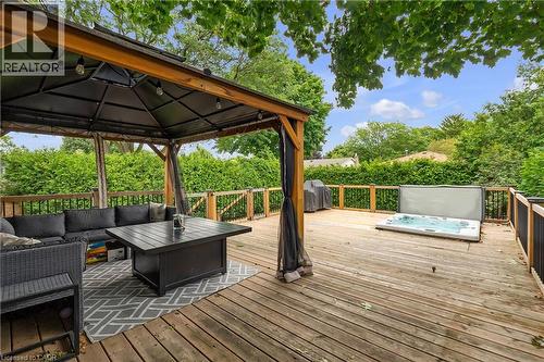 Expansive wood deck featuring a covered gazebo, built-in hot tub, and wood railings with black balusters - 4236 Longmoor Drive, Burlington, ON 