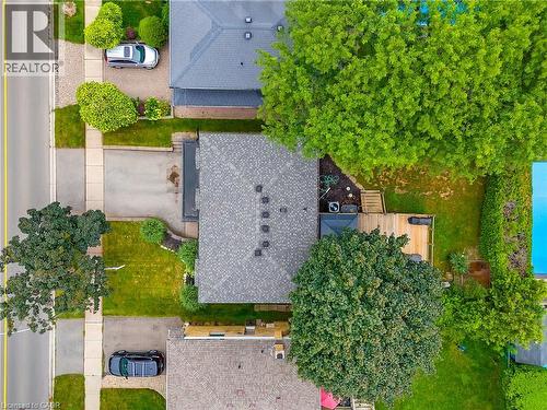 Shingled roof, paved driveway, expansive grassy areas, wooden deck, and mature trees - 4236 Longmoor Drive, Burlington, ON 
