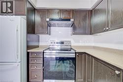 Kitchen featuring dark wood-finish cabinetry, light-toned countertops, and a white subway tile backsplash - 