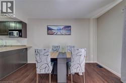 Wood-finish flooring throughout, with crown molding, and a kitchen featuring dark cabinetry, a built-in microwave, and a tile backsplash - 