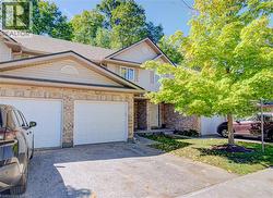 Brick and siding exterior with a shingled roof, two attached garages, and a paved driveway - 