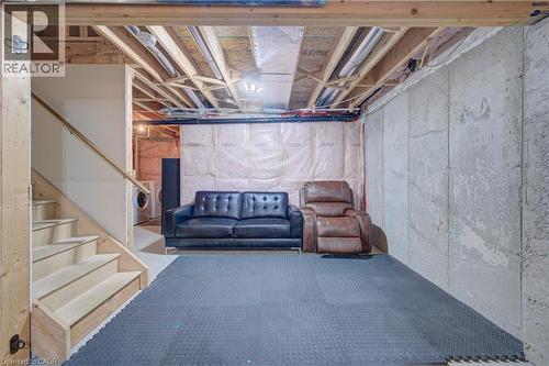 Unfinished basement with exposed ceiling joists and concrete walls, featuring a wood staircase and insulation - 300 Fallowfield Drive Unit# 21, Kitchener, ON 