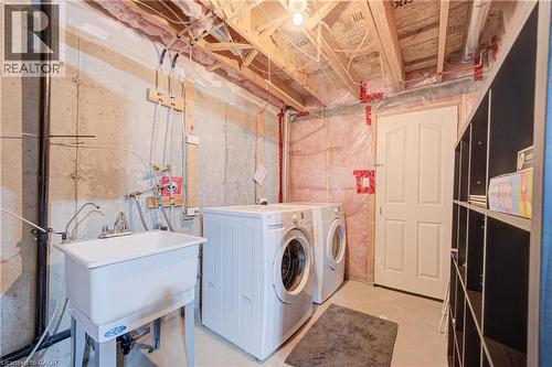 Utility sink, concrete foundation walls, exposed ceiling joists, and a paneled door - 300 Fallowfield Drive Unit# 21, Kitchener, ON 