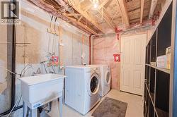 Utility sink, concrete foundation walls, exposed ceiling joists, and a paneled door - 