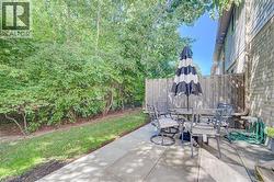 Private patio with paver flooring, wood fencing, and mature perimeter trees - 