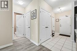White interior doors, white trim, wood-finish flooring, white tile flooring, and neutral wall paint throughout - 