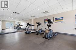 Fitness area featuring rubber flooring, mirrored wall, recessed lighting, and drop ceiling - 