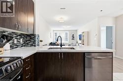 Kitchen featuring dark wood-finish cabinetry, a mosaic tile backsplash, white countertops, and stainless steel appliances - 