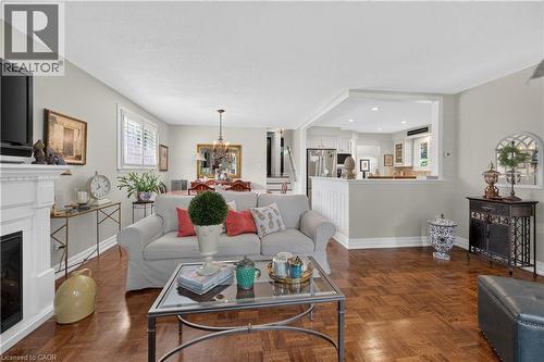 Living area featuring wood-finish flooring, a white mantel, and a dedicated dining space with chandelier - 1434 Dewbourne Crescent, Burlington, ON 