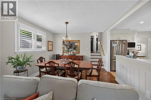 Dining area with wood-finish flooring, white window shutters, and a chandelier - 1434 Dewbourne Crescent, Burlington, ON 