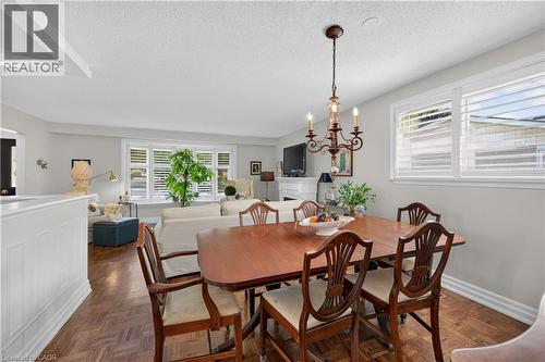 Wood-finish parquet flooring, white wall paneling, white window shutters, and a decorative chandelier - 1434 Dewbourne Crescent, Burlington, ON 