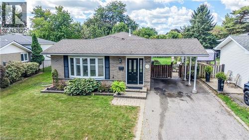 Brick exterior with bay window, covered carport, paved driveway, and mature landscaping - 1434 Dewbourne Crescent, Burlington, ON 
