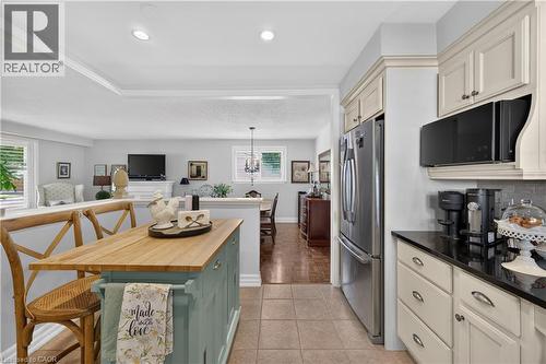 Kitchen featuring tile flooring, cream cabinetry, dark countertops, a stainless steel refrigerator, and recessed lighting - 1434 Dewbourne Crescent, Burlington, ON 