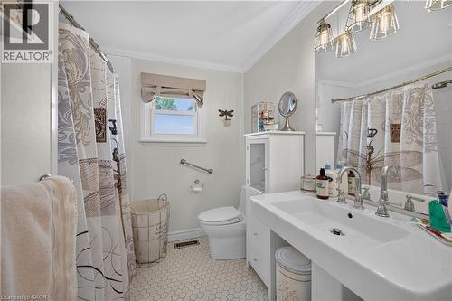 White hex tile flooring, pedestal sink, chrome fixtures, built-in storage cabinet, and window with light-filtering shade - 1434 Dewbourne Crescent, Burlington, ON 
