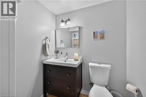 Vanity with integrated sink, dark wood-finish cabinetry, chrome faucet, and rectangular mirror - 1434 Dewbourne Crescent, Burlington, ON 