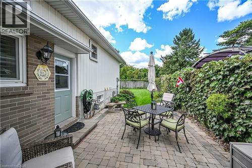 Brick and siding exterior with an accessible side entrance, paver patio, and a privacy fence with established greenery - 1434 Dewbourne Crescent, Burlington, ON 
