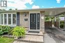 Brick and stone facade featuring a bay window with plantation shutters, a dark entry door with decorative glass, and a covered carport - 1434 Dewbourne Crescent, Burlington, ON 