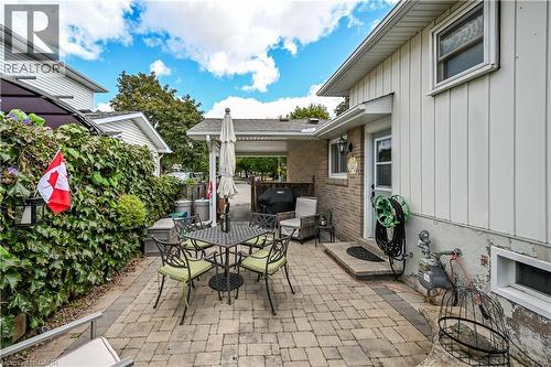 Paver patio with a mature privacy hedge, brick exterior accents, and a covered carport area - 1434 Dewbourne Crescent, Burlington, ON 