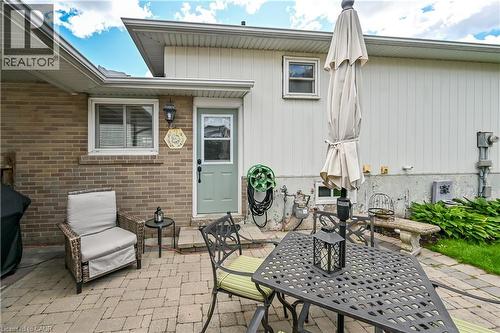 Brick exterior with a light-toned side entrance door, wall-mounted exterior lighting, and a paver patio - 1434 Dewbourne Crescent, Burlington, ON 