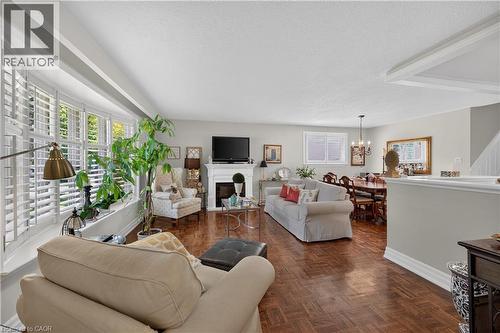 Bay window with interior shutters, wood-finish flooring, white mantel fireplace, ceiling-mounted light fixture, and crown molding - 1434 Dewbourne Crescent, Burlington, ON 
