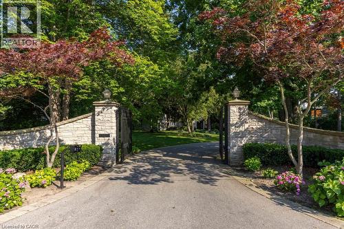 Stone-clad entry wall with wrought iron gates and integrated lighting - 4038 Lakeshore Road, Burlington, ON 