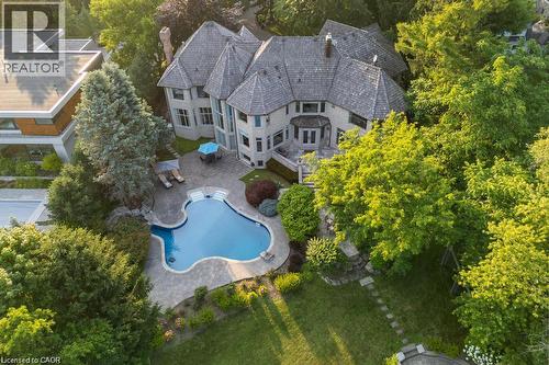 Expansive property featuring a multi-level structure with multiple gables, a large free-form swimming pool, and a paver patio surround - 4038 Lakeshore Road, Burlington, ON 