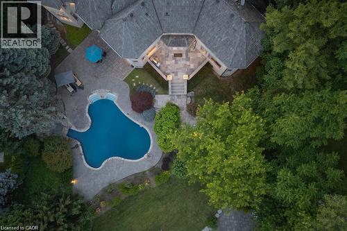 Property featuring a curvilinear swimming pool, extensive stone patio, mature landscaping, and multi-level outdoor entertaining areas - 4038 Lakeshore Road, Burlington, ON 