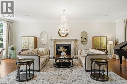 Hardwood flooring, ornate fireplace with stone surround, crown molding, large windows, and a decorative chandelier - 4038 Lakeshore Road, Burlington, ON 