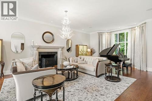 Hardwood flooring, ornate fireplace with stone mantel, bay window, crown molding, and a chandelier - 4038 Lakeshore Road, Burlington, ON 