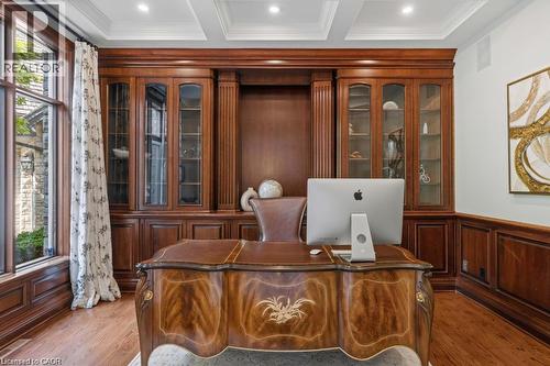 Custom built-in wood cabinetry with glass-front display, detailed wood paneling, wood-finish flooring, and recessed ceiling lighting - 4038 Lakeshore Road, Burlington, ON 