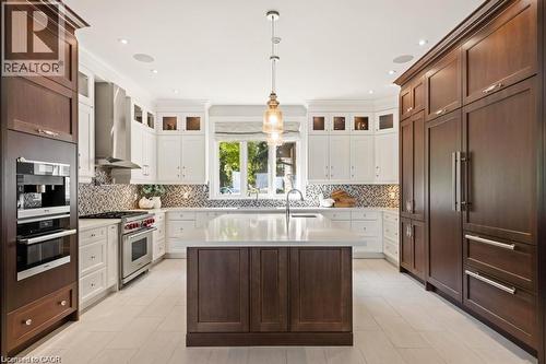 Gourmet kitchen featuring a large central island, integrated appliances, two-tone cabinetry, and a mosaic tile backsplash - 4038 Lakeshore Road, Burlington, ON 