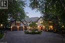 Stone and timber-frame exterior featuring a multi-car garage, circular driveway, established landscaping, and an ornate fountain - 4038 Lakeshore Road, Burlington, ON 