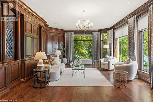 Rich wood paneling, dark wood-finish flooring, a contemporary chandelier, recessed lighting, and large windows with integrated shades - 4038 Lakeshore Road, Burlington, ON 