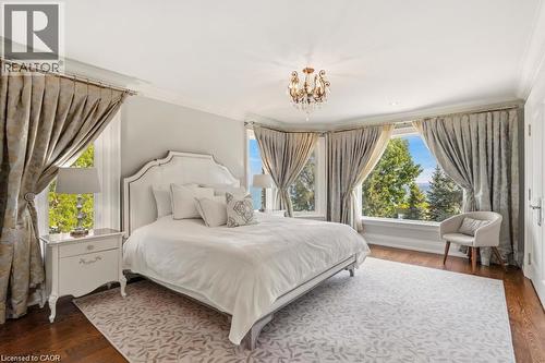 Bay window offering expansive scenery, dark wood-finish flooring, ornate chandelier, and white paneled door - 4038 Lakeshore Road, Burlington, ON 