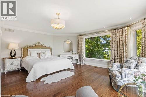 Hardwood flooring, expansive bay window, ornate ceiling light fixture, crown molding, and a decorative built-in vanity with mirror - 4038 Lakeshore Road, Burlington, ON 