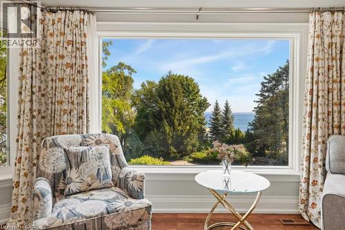 Expansive bay window framing a captivating water view, complemented by wood-finish flooring and white trim - 4038 Lakeshore Road, Burlington, ON 