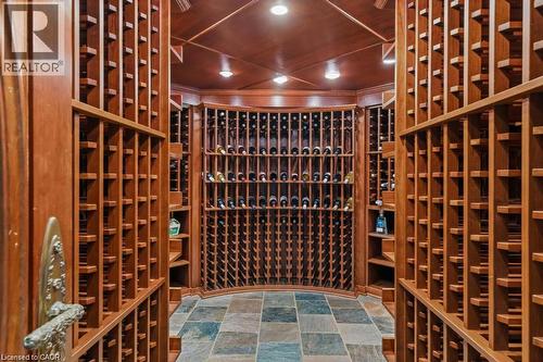 Custom wine cellar featuring extensive wood racking, wood-paneled ceiling, recessed lighting, and multi-tone square tile flooring - 4038 Lakeshore Road, Burlington, ON 
