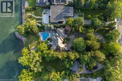 Waterfront property featuring extensive mature landscaping, a freeform swimming pool, and a stone-clad multi-level residence with a gabled roof - 