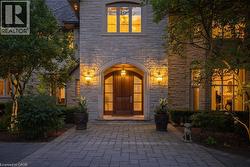Stone exterior facade with a prominent arched entry, wood-paneled double doors, and decorative outdoor lighting - 