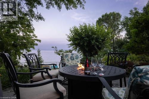 Paved patio with a built-in fire pit and surrounding mature trees - 4038 Lakeshore Road, Burlington, ON 
