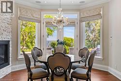 Bay window with multiple glass doors, stacked stone fireplace, wood-finish flooring, and crown molding - 