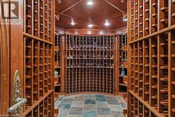 Custom wine cellar featuring extensive wood racking, wood-paneled ceiling, recessed lighting, and multi-tone square tile flooring - 