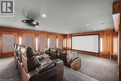Dedicated media room featuring wood paneling, a large projection screen, integrated projector, and recessed lighting - 