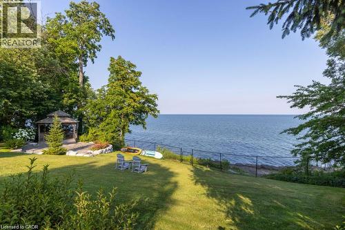 Expansive green lawn with mature trees and a charming gazebo, overlooking a vast body of water - 4038 Lakeshore Road, Burlington, ON 