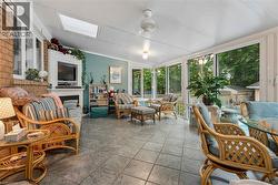 Sunroom with full-height windows, skylight, ceiling fan, tile flooring, and a built-in fireplace - 
