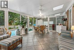 Sunroom with expansive window walls, tile flooring, ceiling fan, and skylights - 