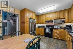 Kitchen with wood cabinetry, dark countertops, tiled flooring, and stainless steel refrigerator - 