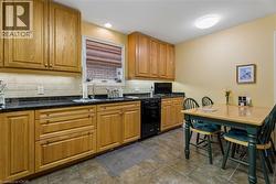 Kitchen featuring wood cabinetry, dark countertops, a tiled backsplash, and recessed lighting - 