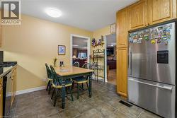 Stainless steel refrigerator, wood-finish cabinetry, dark countertop, and tile flooring - 